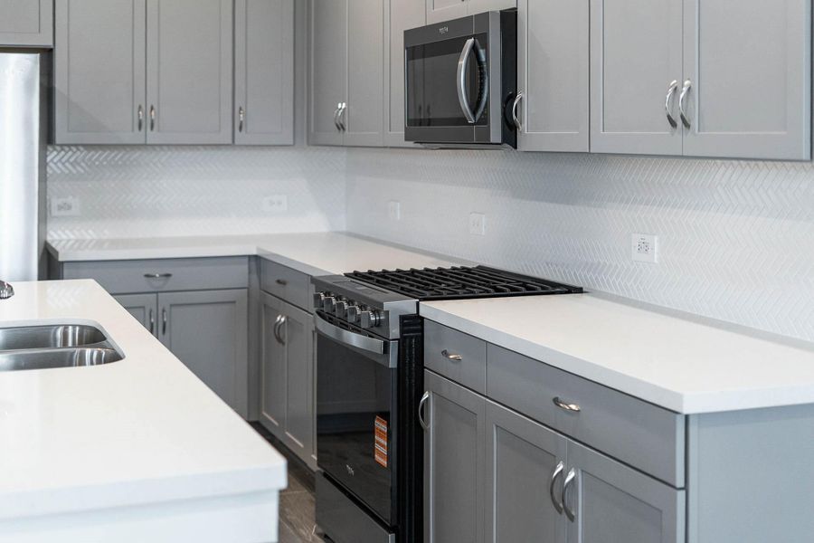 High-end white quartz countertops are perfectly paired with a detailed white herringbone tile backsplash, creating a bright and elegant workspace that complements the rich grey cabinetry. High-end white quartz countertops are perfectly paired with a detailed white herringbone tile backsplash, creating a bright and elegant workspace that complements the rich grey cabinetry.