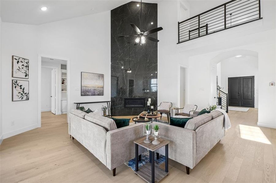 Living area featuring high vaulted ceiling, a premium fireplace, light wood-type flooring, arched walkways, and ceiling fan Living area featuring high vaulted ceiling, a premium fireplace, light wood-type flooring, arched walkways, and ceiling fan