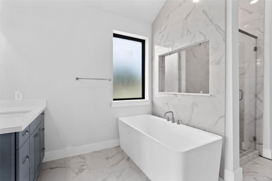This alternate view of the primary bathroom showcases a large soaking tub perfect for unwinding after a long day, walk-in shower with a stylish tile surround, and a large walk-in closet!