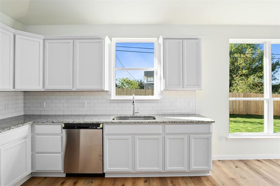 Kitchen featuring dishwasher, decorative backsplash, white cabinetry, and plenty of natural light Kitchen featuring dishwasher, decorative backsplash, white cabinetry, and plenty of natural light