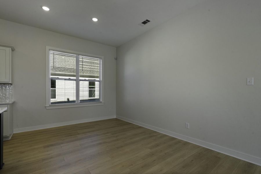 Recessed ceiling lighting, wood-finish flooring, white trim, and a window with blinds