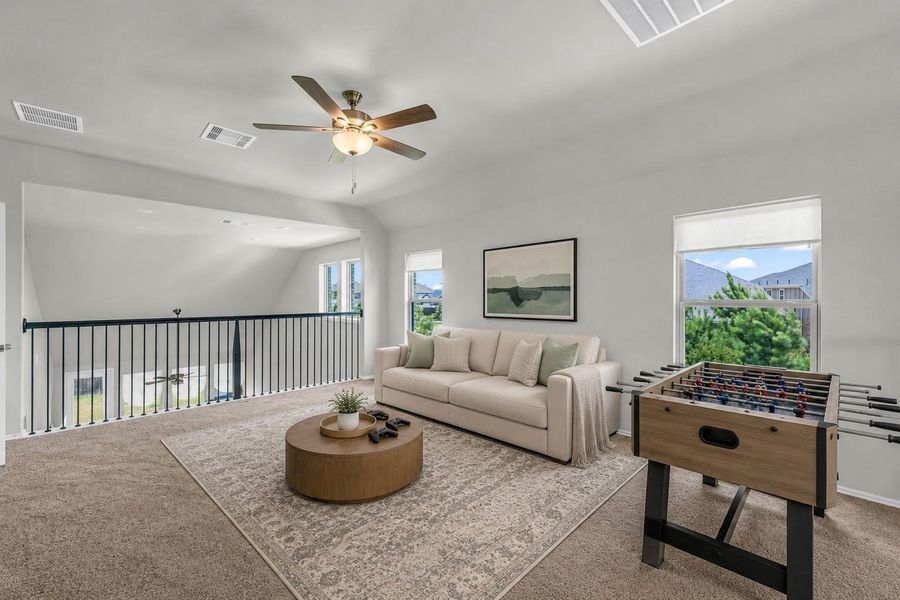 An alternate view of the spacious game room highlights a wall of windows that floods the carpeted loft space with natural light.**Virtually staged An alternate view of the spacious game room highlights a wall of windows that floods the carpeted loft space with natural light.**Virtually staged