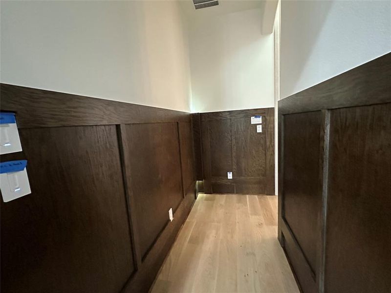 Detailed view of wood finished floors and a wainscoted wall
