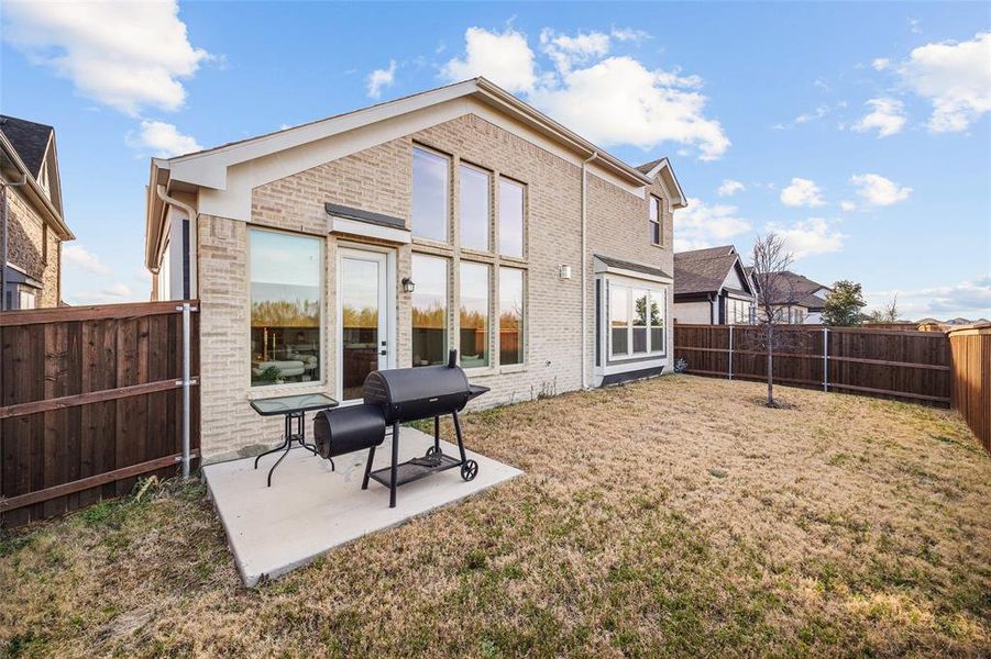 Back of property featuring a fenced backyard, brick siding, and a patio