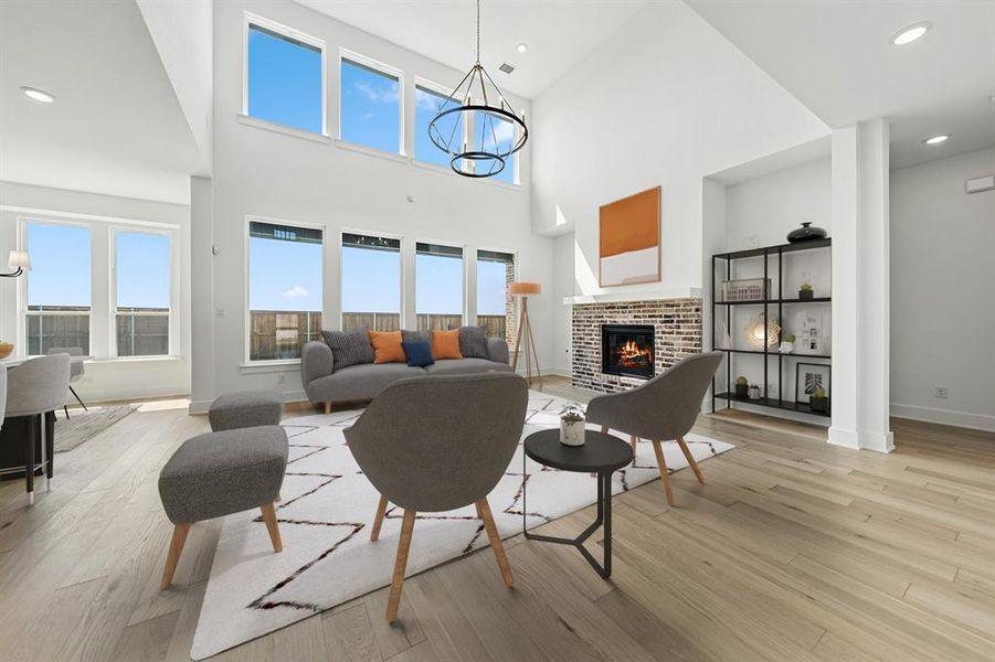 Living area with a chandelier, recessed lighting, a brick fireplace, light wood-style floors, and a high ceiling