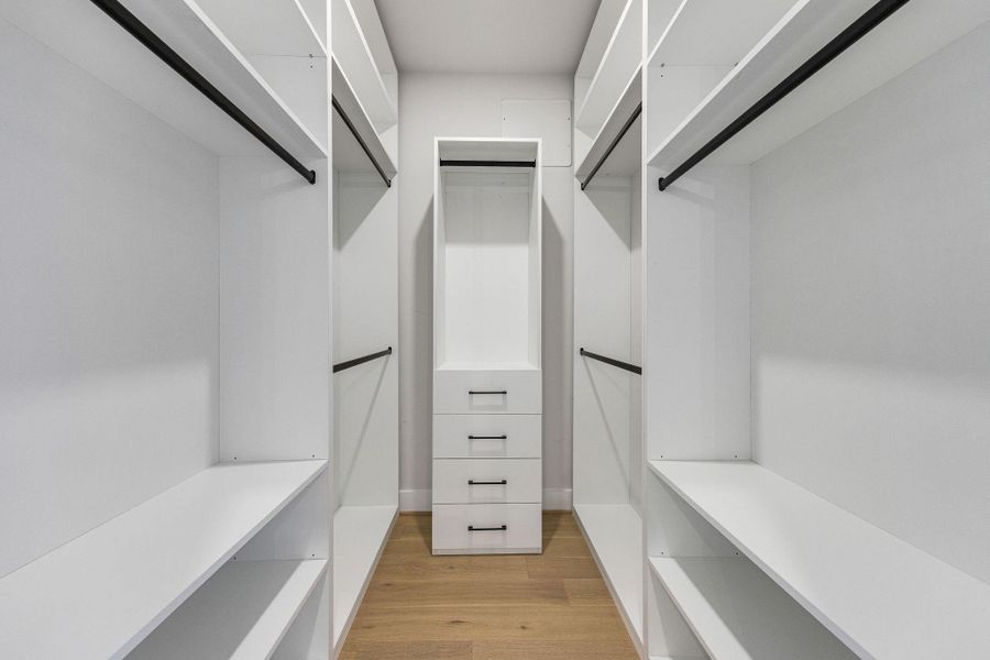 Primary bedroom oversized custom walk-in closet with built-in shelving, ample hanging space, and modern organization designed for both style and functionality.