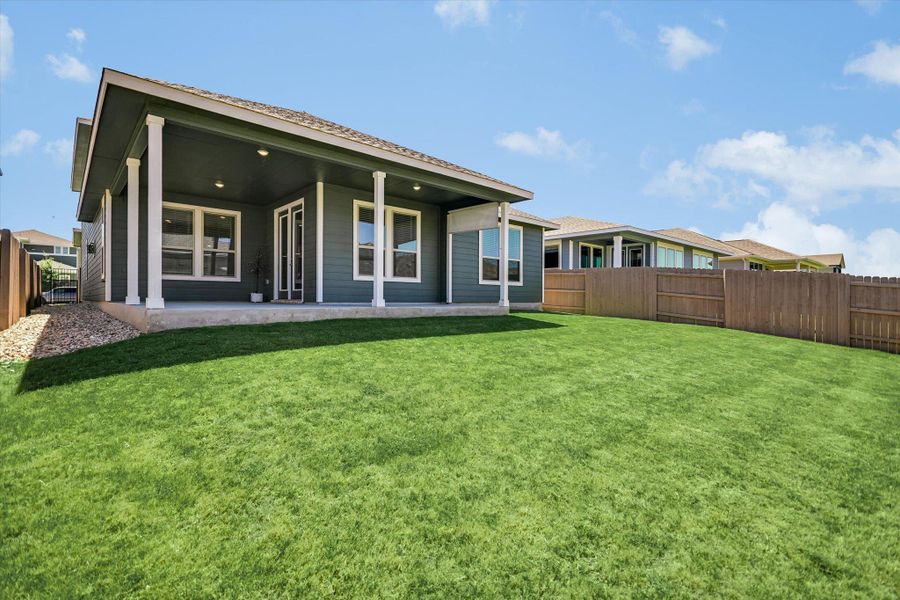 A deep covered back porch overlooks a level lawn enclosed by a wooden privacy fence. A deep covered back porch overlooks a level lawn enclosed by a wooden privacy fence.