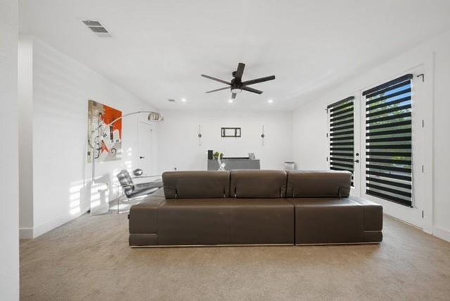 Carpeted living area featuring a ceiling fan with integrated lighting, recessed lighting, and two French doors with horizontal blinds