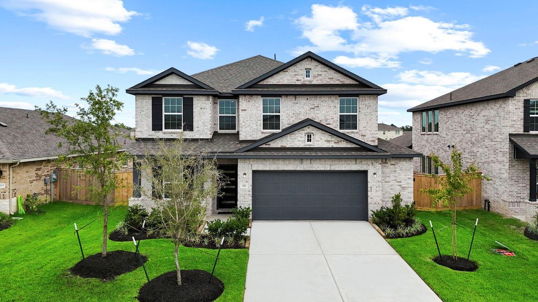 Front elevation showcases the home’s timeless brick exterior, upgraded gray garage door, and manicured landscaping, all nestled on a desirable lot in the peaceful Massey Oaks community.