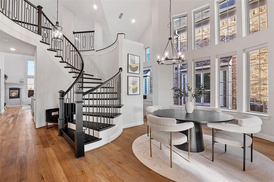 Dining room with an inviting chandelier, a high ceiling, wood-type flooring, and stairs