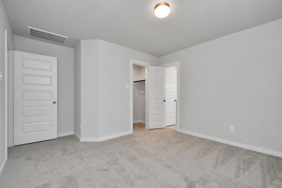 generously sized secondary bedrooms, showcasing 5-panel doors with modern hardware, large windows adorned with privacy blinds, and spacious closets boasting sleek and contemporary finishes. Sample photo of completed home with similar floor plan. Actual colors and selections may vary.