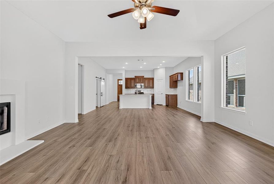 Unfurnished living room with a glass covered fireplace, dark wood-style floors, recessed lighting, and a ceiling fan