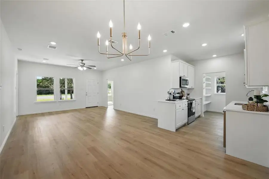 Kitchen with appliances with stainless steel finishes, a sink, a ceiling fan, light wood finished floors, and recessed lighting Kitchen with appliances with stainless steel finishes, a sink, a ceiling fan, light wood finished floors, and recessed lighting