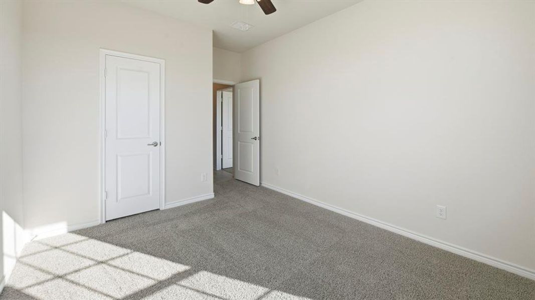 Carpeted interior room featuring neutral wall finishes, white trim, and a ceiling fan