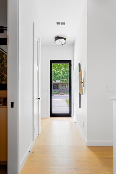 Hallway with baseboards, wood finished floors, and visible vents