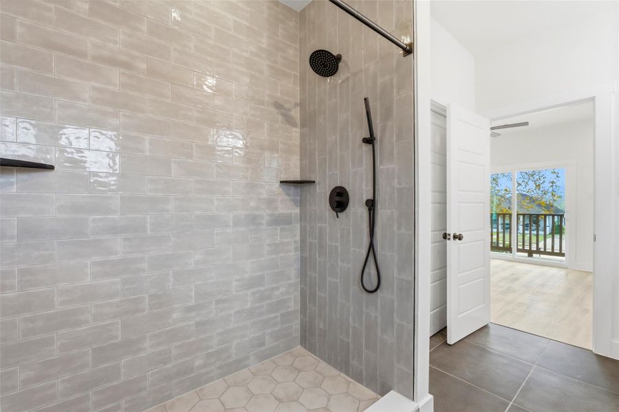 Primary bath offering a spacious walk in shower with built-in shelving and multi-function shower head.