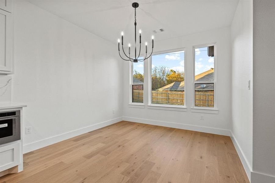Unfurnished dining area featuring light wood-type flooring and a chandelier