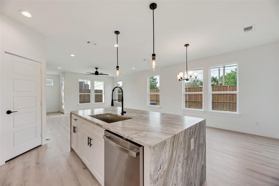 Kitchen with light stone counters, dishwasher, a ceiling fan, white cabinetry, and light wood-style floors