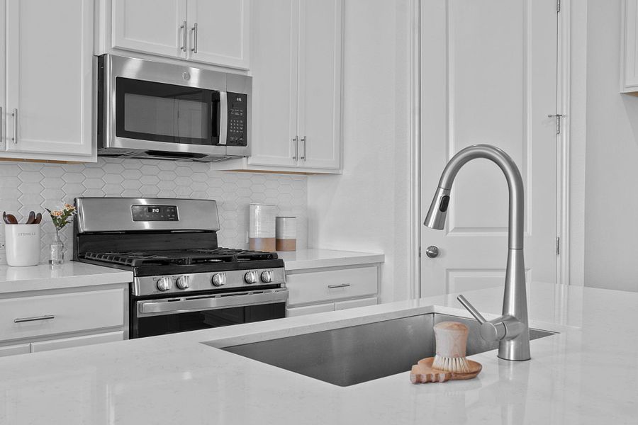 Kitchen featuring appliances with stainless steel finishes, white cabinetry, tasteful backsplash, and a sink