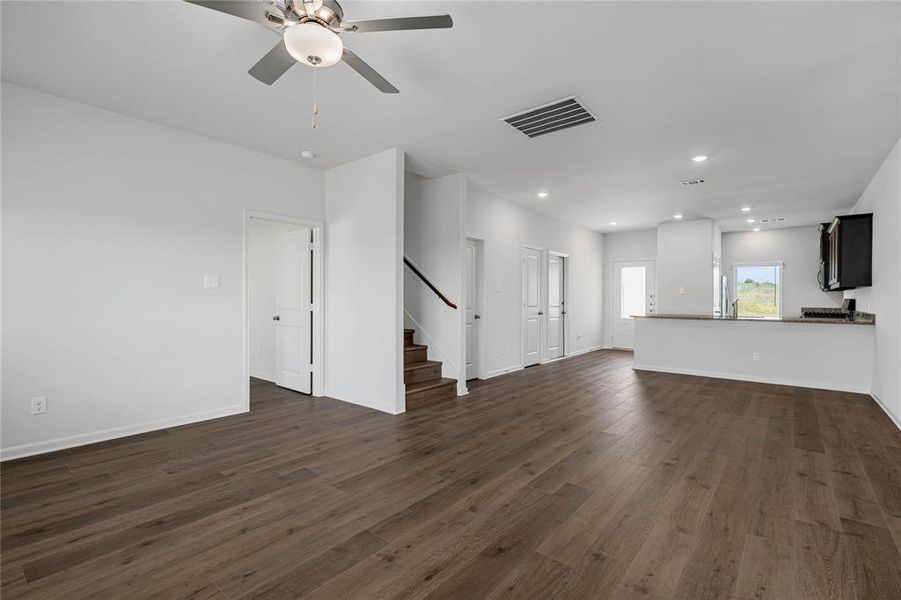 Unfurnished living room featuring recessed lighting, dark wood-type flooring, stairway, and a ceiling fan