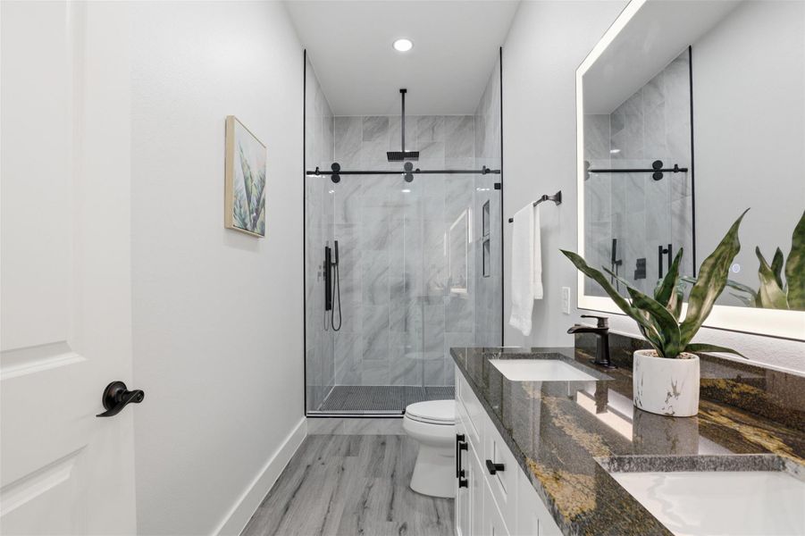 Contemporary bathroom featuring a dual vanity with a polished granite countertop and undermount sinks