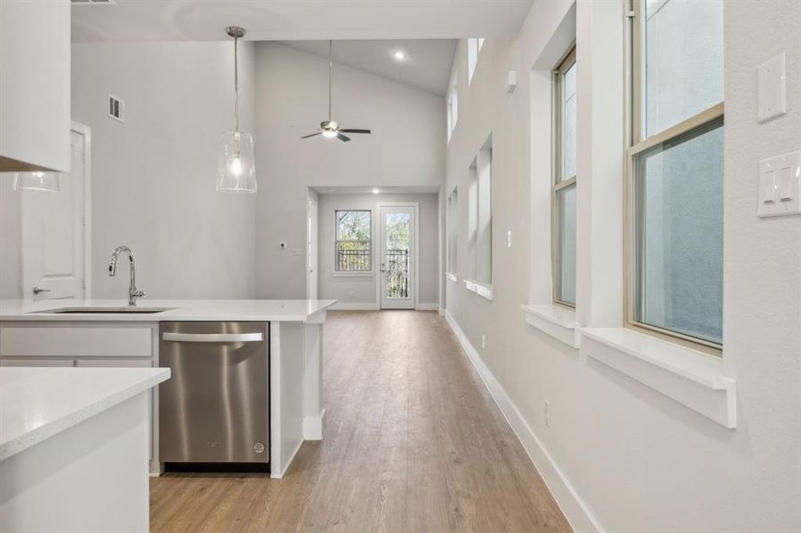 Kitchen featuring decorative pendant light fixtures, white cabinetry, whirlpool dishwasher, farm sink, and light wood-type flooring