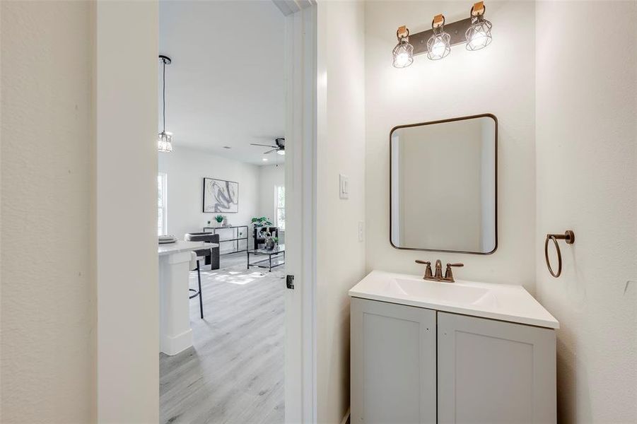 Half bathroom featuring light wood-style floors, vanity, and a ceiling fan
