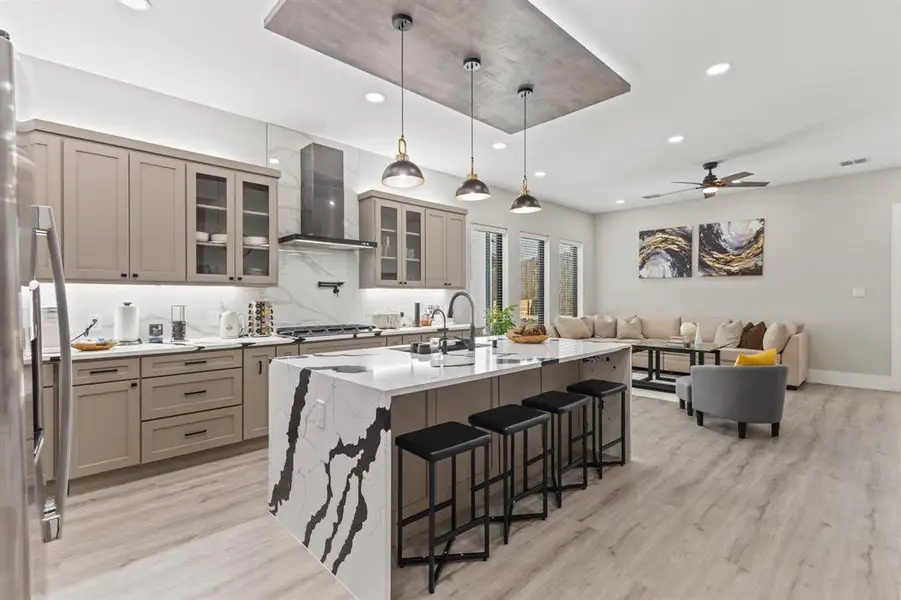 Kitchen featuring gray cabinetry, decorative light fixtures, recessed lighting, a kitchen island with sink, and glass insert cabinets