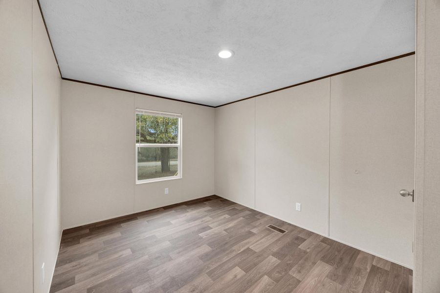 Empty room with light wood-style floors, a textured ceiling, ornamental molding, and recessed lighting