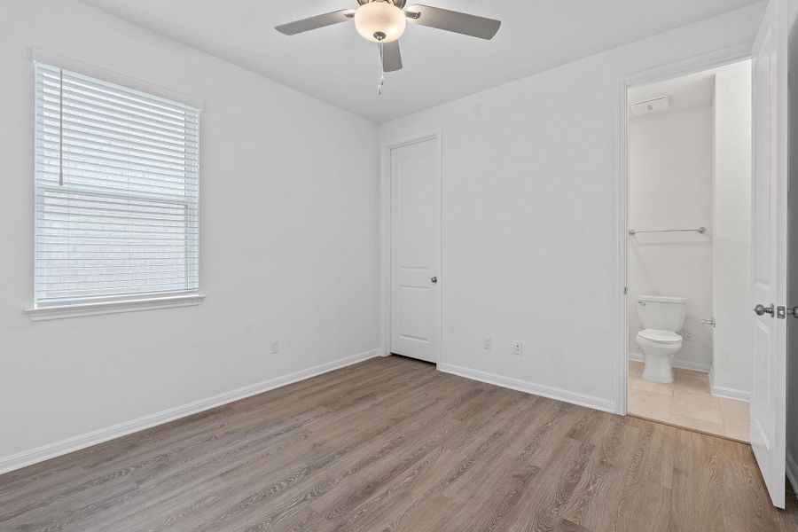 Unfurnished bedroom featuring light wood-style flooring, ensuite bath, baseboards, and a ceiling fan