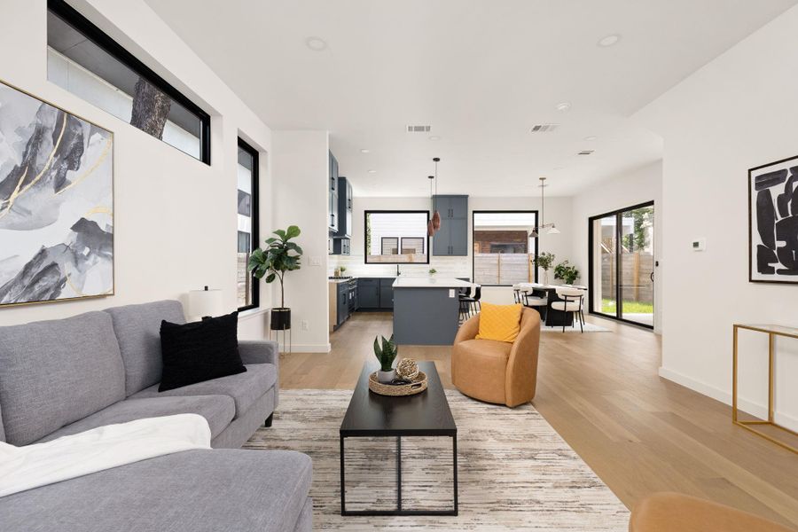 An open floorplan seamlessly connects the living area, kitchen, and dining space, all illuminated by abundant natural light.