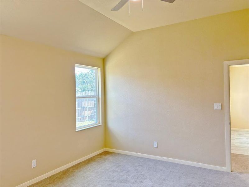 Carpeted empty room with lofted ceiling and a ceiling fan