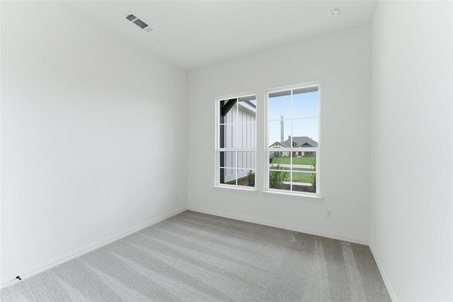This room features bright white walls, two windows providing abundant natural light, and plush grey carpeting