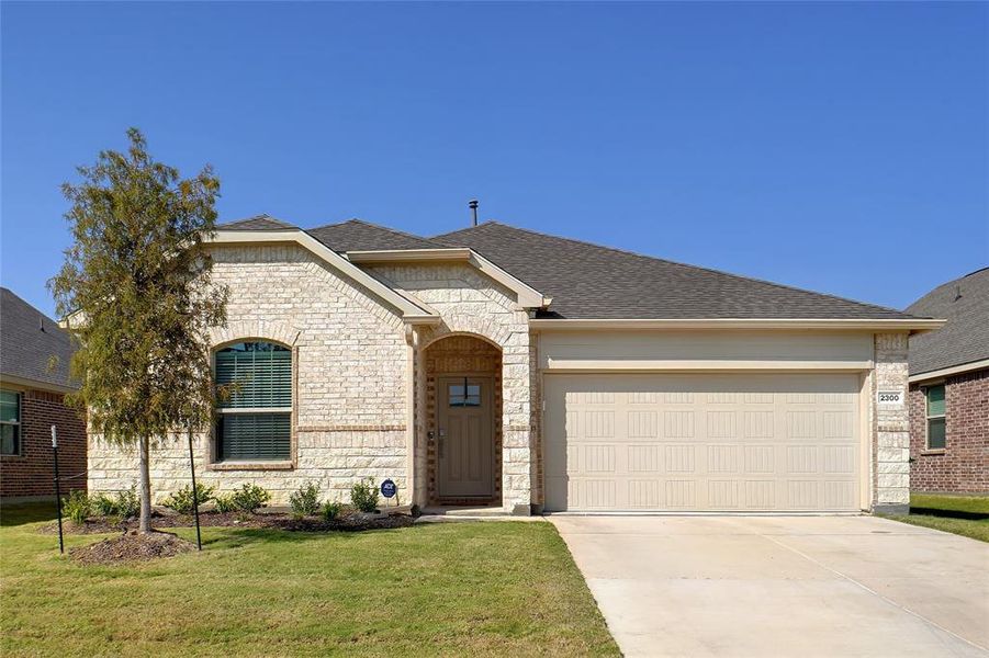 View of front of home with a garage and a front lawn