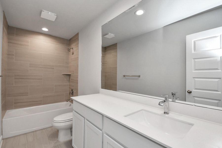 Secondary bath features tile flooring, bath/shower combo with tile surround, light stained wood cabinets, beautiful light countertop. Sample photo of completed home with similar floor plan. Actual colors and selections may vary. Secondary bath features tile flooring, bath/shower combo with tile surround, light stained wood cabinets, beautiful light countertop. Sample photo of completed home with similar floor plan. Actual colors and selections may vary.