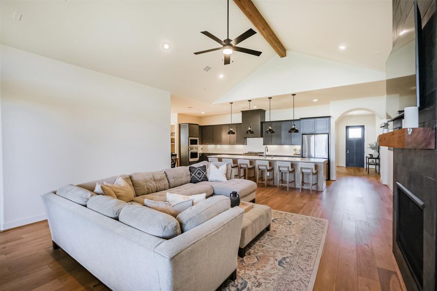 View of the inviting living room pre-wired for sound with fireplace, vaulted ceiling, and island seating area.