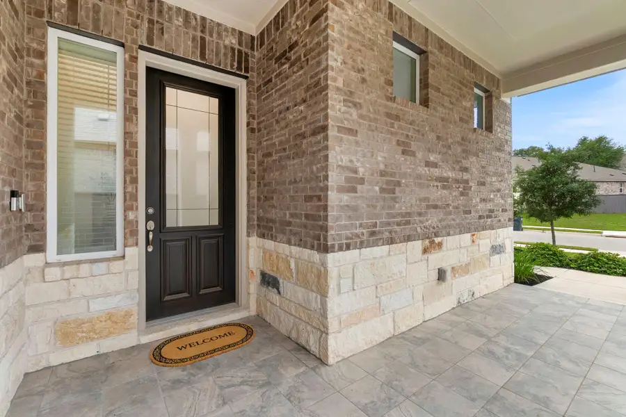Exterior featuring a dark wood-finish entry door with glass inserts, flanked by a side light window with horizontal blinds