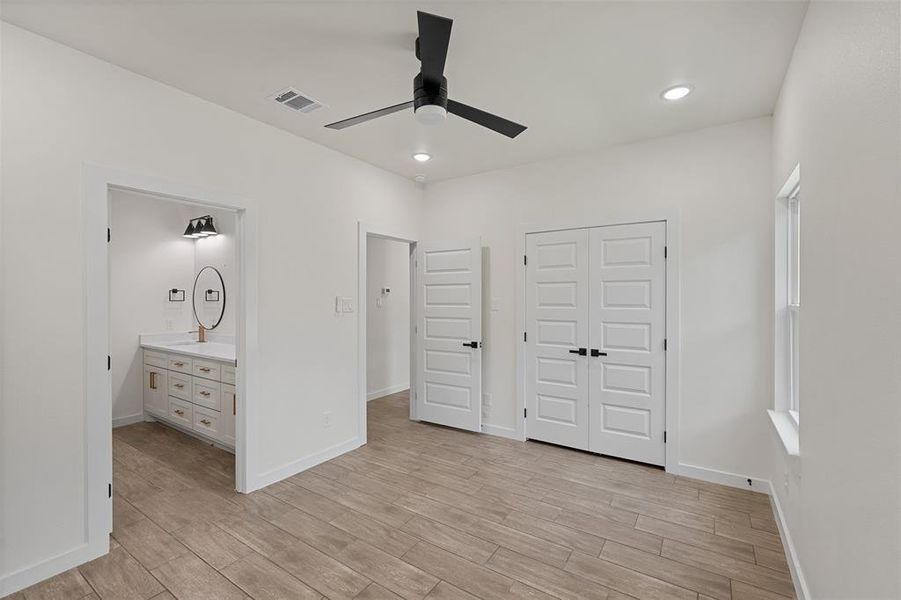 Interior space featuring wood-finish flooring, white walls, and a contemporary black ceiling fan