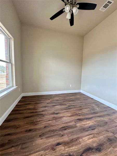 Spare room featuring ceiling fan, a healthy amount of sunlight, and dark hardwood / wood-style floors