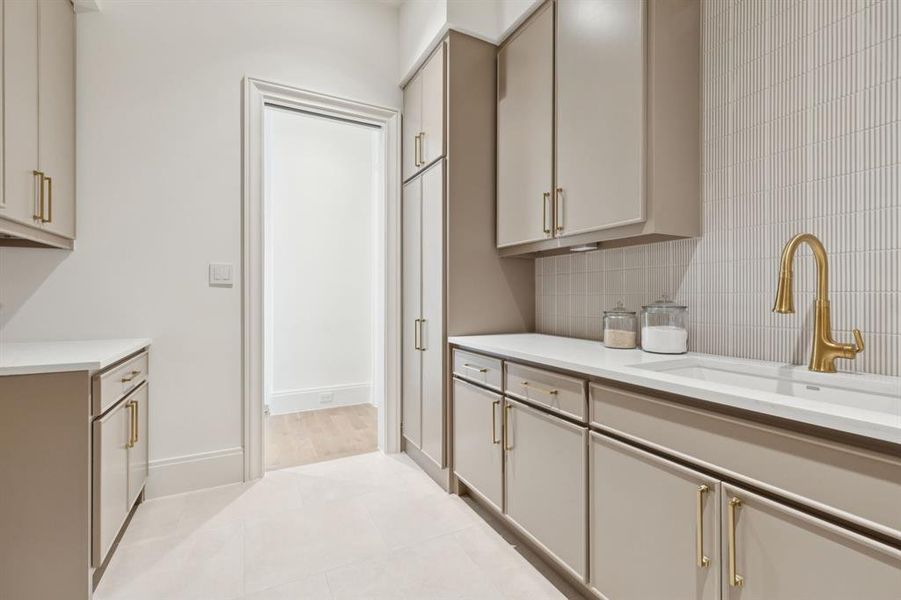 Kitchen with decorative backsplash, cream cabinets, light tile patterned floors, and light stone countertops
