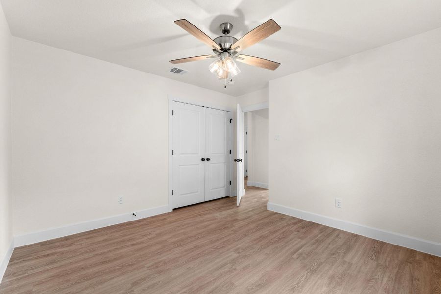 Unfurnished bedroom with light wood-type flooring, a ceiling fan, and a closet