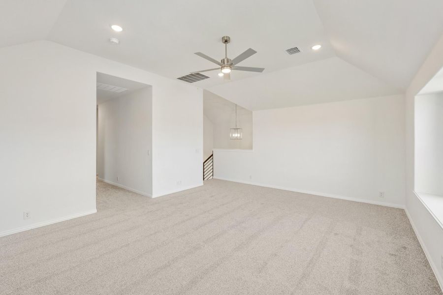 Empty living room with vaulted ceiling, ceiling fan, carpet flooring, and staircase opening Empty living room with vaulted ceiling, ceiling fan, carpet flooring, and staircase opening
