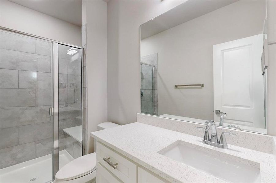 Bathroom featuring an enclosed shower, vanity, and toilet