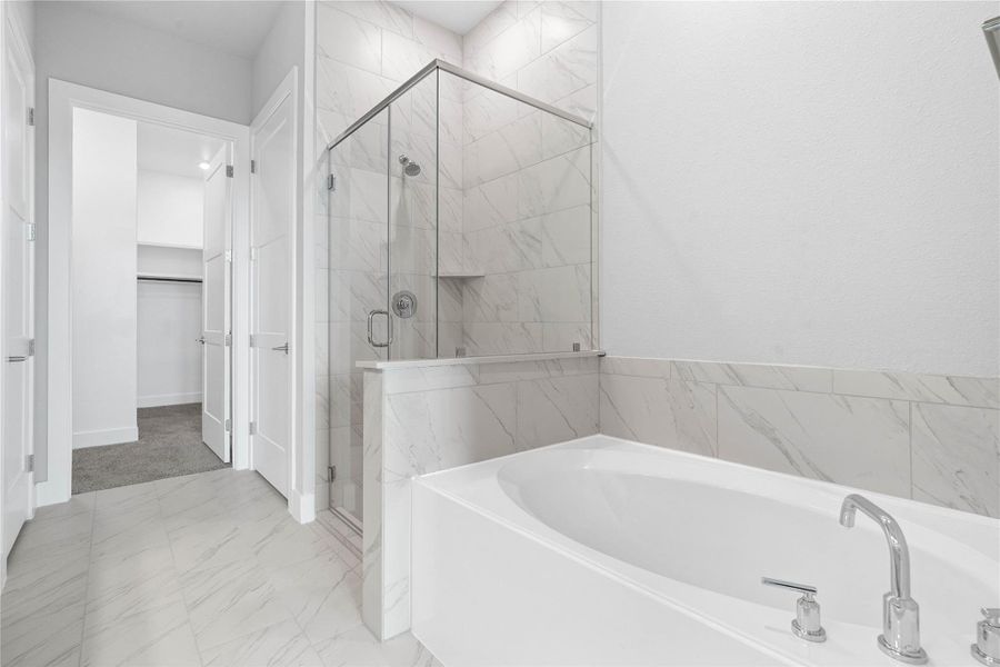 Indulge in relaxation within this spa-inspired primary bathroom, offering both a quick shower and a tranquil soaking experience. The walk-in shower is glass enclosed with modern tile walls and sleek finishes.