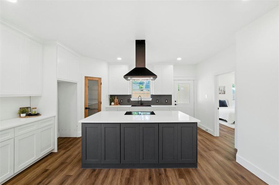 Kitchen featuring exhaust hood, dark wood-style flooring, white cabinets, decorative backsplash, and recessed lighting