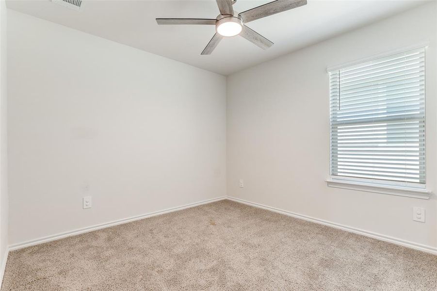 Carpeted room featuring a ceiling fan with integrated lighting, a window with blinds, and white trim Carpeted room featuring a ceiling fan with integrated lighting, a window with blinds, and white trim