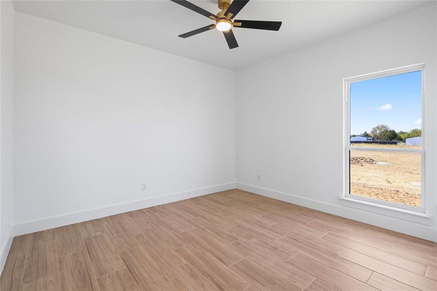 Spare room featuring light wood finished floors and a ceiling fan Spare room featuring light wood finished floors and a ceiling fan
