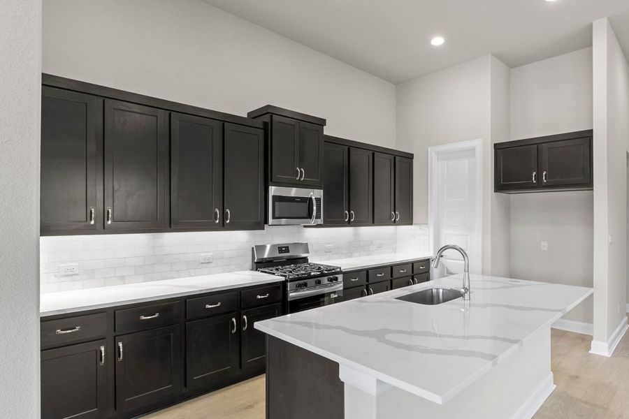 Image of kitchen with dark cabinets and light flooring with a island