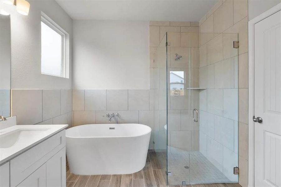 A well-appointed bathroom features a modern freestanding tub, a spacious glass-enclosed shower, and wood-look tile flooring.