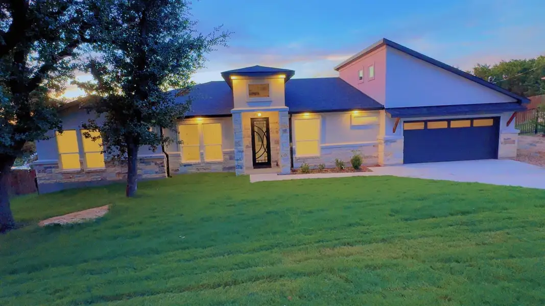 View of front of house with a garage, concrete driveway, a front lawn, and stone siding